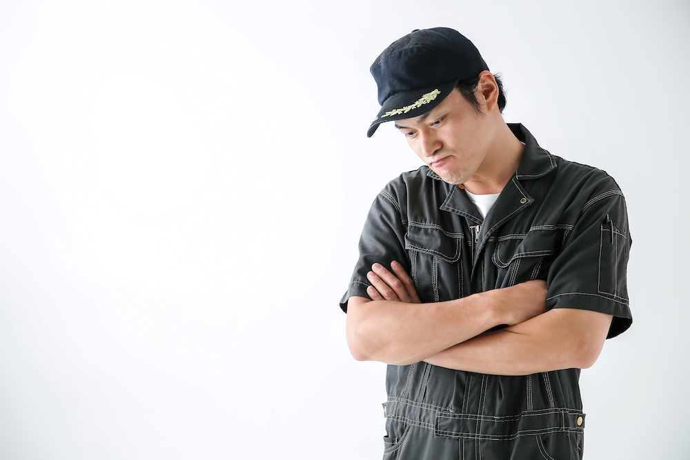 腕を組んで悩む男性